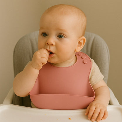 bébé portant un bavoir en silicone rose pendant le repas